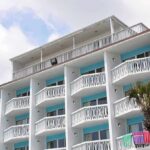 Exterior view of a beachfront hotel with balconies and colorful towels hanging