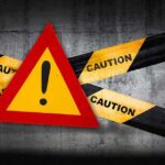 Warning sign with caution tape against a concrete background