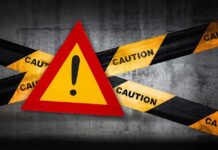 Warning sign with caution tape against a concrete background