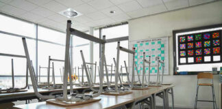 Empty classroom with chairs on top of desks.