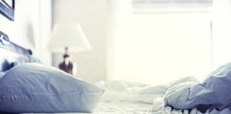 A cozy unmade bed with soft pillows and bedding in a well-lit room