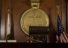 A judges bench in a courtroom with a gavel and flags