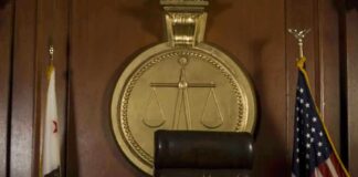 A judges bench in a courtroom with a gavel and flags