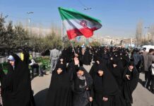 Iran Hangs Wrestling Champ Publicly Group of women in black attire marching with an Iranian flag