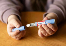 Hands holding an Ozempic injection pen.