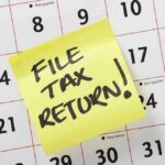 A sticky note on a calendar reminding to file tax return