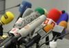 A collection of various microphones arranged for a press conference