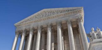 The Supreme Court building featuring grand columns and statues under a clear blue sky