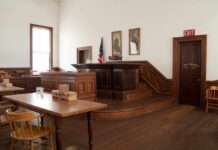 Interior of a historic courtroom with wooden furniture and an American flag