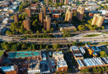 Hidden Agenda: NYC’s Housing Takeover? Aerial view of urban area with tall buildings and freeway.