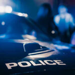 23 Shot in CHAOS — Oklahoma Lake Horror Police car with blurred figures in the background.