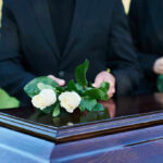 Protest Chaos Erupts—Kash Patel Funeral Interrupted! People placing white roses on a casket.