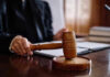 Court STUNNER: Trump’s $83M Payout HALTED! Judge holding gavel in courtroom.