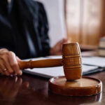 Court STUNNER: Trump’s $83M Payout HALTED! Judge holding gavel in courtroom.