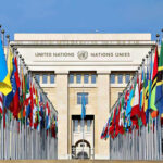 Kremlin’s Peace Talk Chaos: Real Intentions Exposed United Nations building with numerous national flags outside.