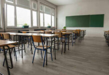 Outrage Erupts Over AI Classroom Control Empty classroom with desks, chairs, windows, and chalkboard.