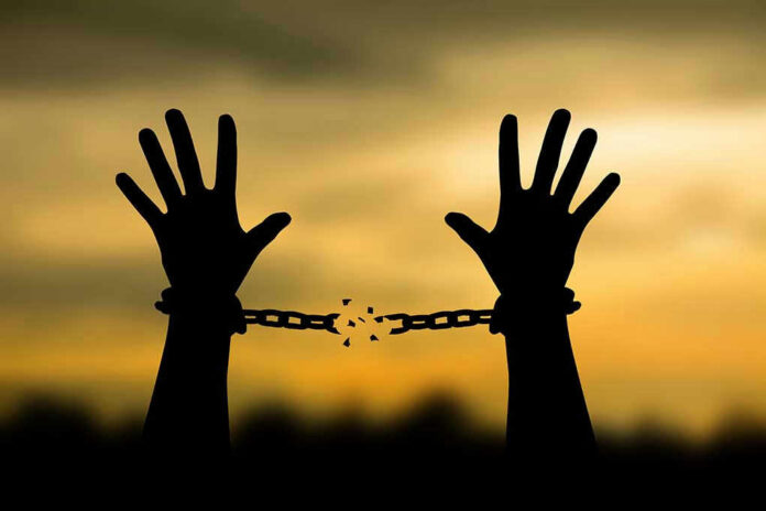 698153707 Hands breaking free from chains at sunset.