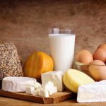 Hidden Dairy Power Play: Is Your Milk at Risk? Assorted dairy products including cheese, milk, and eggs on a wooden surface
