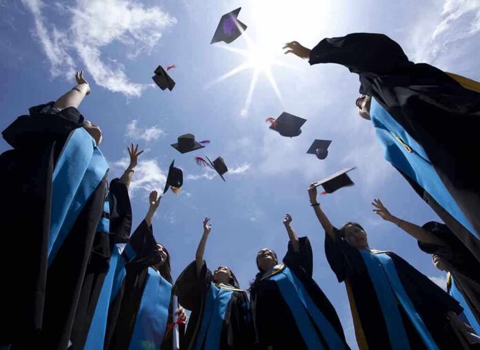 shutterstock_115335829 Graduating students celebrating by throwing their caps into the air under a bright blue sky