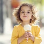 Junk Food Rewires Kids’ Brains—SHOCKING New Findings! A young child with curly hair holding an ice cream cone outdoors
