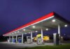 A gas station at night with illuminated fuel pumps and a convenience store