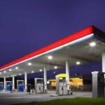 Trump SLASHES Gas Tax Amid $4.52 Gallon Shock A gas station at night with illuminated fuel pumps and a convenience store