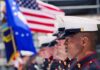 Massive Military Reversal on Vaccine Policy U.S. Marines in uniform standing in formation with flags in the background