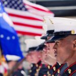 Massive Military Reversal on Vaccine Policy U.S. Marines in uniform standing in formation with flags in the background