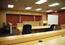 Massive Theft from Kids’ Food Program: 41-Year Sentence Interior view of an empty courtroom with wooden furniture and American flags