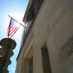 ISIS Drone Plot Tied to Ex-Sailor American flag at Department of Justice building exterior.