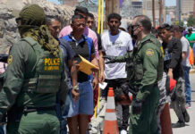 Border patrol agents inspecting group of individuals in line.