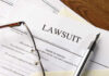 23andMe Breach: The Payout Shock Lawsuit papers with glasses and pen on table.