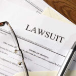 Lawsuit papers with glasses and pen on table.