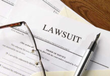 Lawsuit papers with glasses and pen on table.