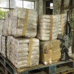 Stacked packages on a pallet with a rifle.