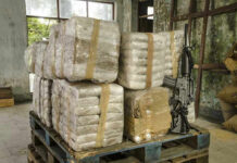 Fentanyl Math Flips The Border Debate Stacked packages on a pallet with a rifle.