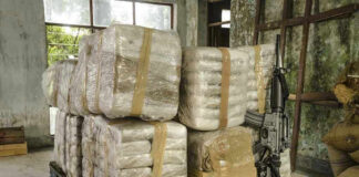 Stacked packages on a pallet with a rifle.