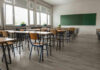 Predator Roamed Locker Rooms — How? Empty classroom with desks, chairs, windows, and chalkboard.