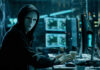 System Failure Lets Ex-Probation Warn Cartel Person wearing mask and hoodie at computer desk.