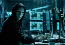 System Failure Lets Ex-Probation Warn Cartel Person wearing mask and hoodie at computer desk.