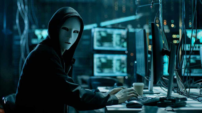 680078920 Person wearing mask and hoodie at computer desk.