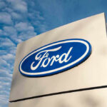 White House Curveball Rattles Ford, GM Ford logo sign against blue sky.