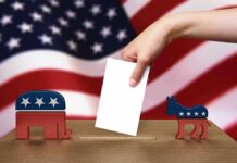 Feds Grab Voter Files — What’s Hidden? A hand placing a ballot into a box with political symbols on either side against a backdrop of the American flag