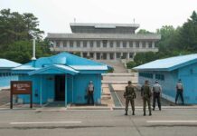 Hezbollah Pause—Who Really Wins? Military personnel standing near blue buildings at a border crossing