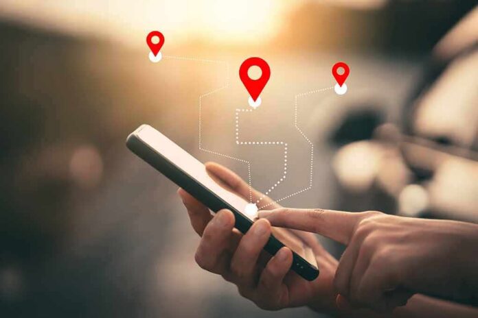 shutterstock_1631344318 Person using a smartphone with location markers displayed on the screen