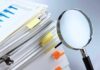 Fake Nurses Flood Hospitals — Diploma Mill Exposed Stack of documents with a magnifying glass beside it
