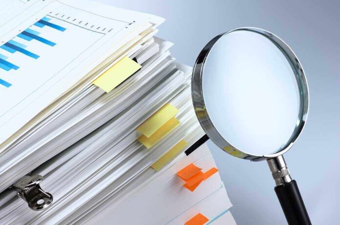 Investigate,And,Analyze.,Scanning,Business,Documents.,Magnifying,Glass,And,Stack Stack of documents with a magnifying glass beside it