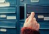 A hand holding a key, opening a blue mailbox drawer