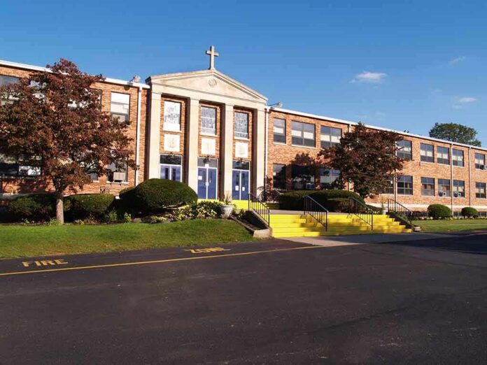 shutterstock_18910786 Exterior view of a brick school building with yellow steps and a cross on top