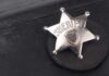 Badge-Toting Predator Exposed A silver sheriff badge resting on a black leather surface
